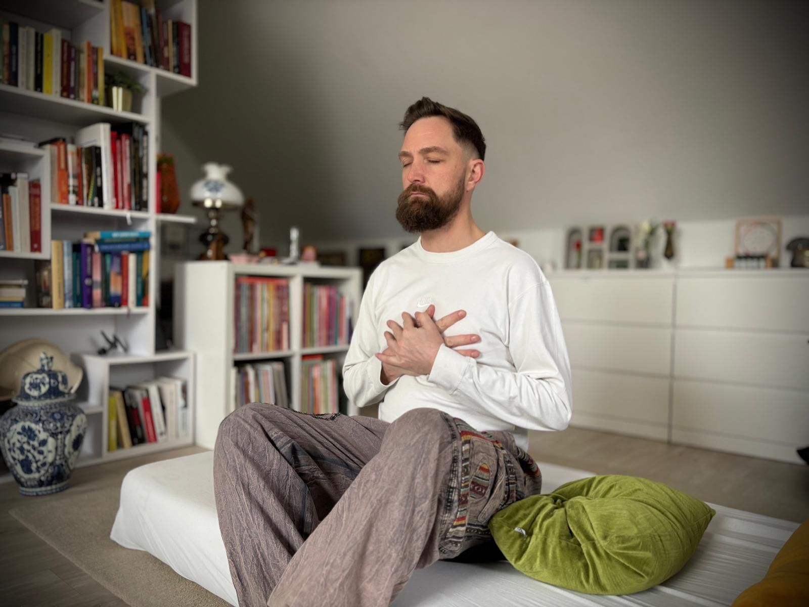 Sven Van Boven zit rustig rechtop met gesloten ogen en beide handen op zijn hart tijdens een ademoefening.